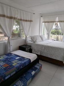 a bedroom with two beds and a window at Finca Mirador la Giralda in Roldanillo