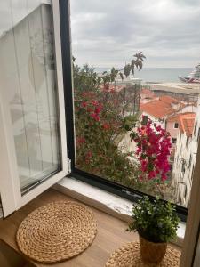 a window with a view of the ocean and flowers at Alfama authentic Lisbon in Lisbon