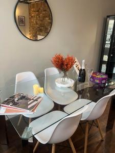 a glass table with two white chairs and a mirror at Stylish Apartment in CENTRAL LONDON in London