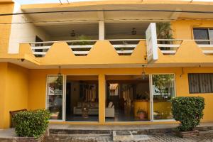 a yellow house with a porch and a balcony at Hotel San Lorenzo in Barra de Navidad