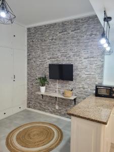a living room with a brick wall with a tv at Azores village apartments in Fontinhas