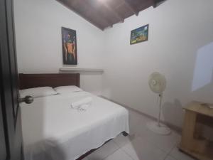 a white bedroom with a bed and a fan at Apartahotel San Miguel in San Gil