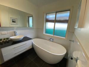 łazienka z dużą białą wanną i umywalką w obiekcie Beautiful 3BR Home by Dandenong Creek w mieście Bayswater
