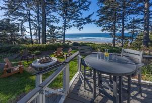 a table and chairs on a deck with a view of the beach at Tyee Lodge Bed And Breakfast in Newport