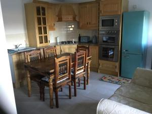 a kitchen with a wooden table and wooden chairs at Cosy Cottage Broadford in Broadford