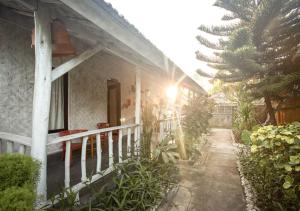 een huis met een veranda en een balkon met bomen bij Fullmoon Bungalows in Toyapakeh