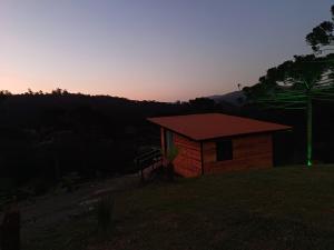 uma pequena cabana com um pôr-do-sol ao fundo em Recanto do Ipê (cabana 02) em Urubici