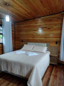 a bedroom with a white bed with wooden walls at Recanto do Ipê (cabana 02) in Urubici