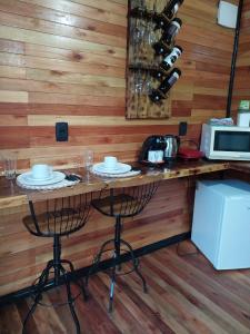 um bar com duas cadeiras e um balcão com garrafas de vinho em Recanto do Ipê (cabana 02) em Urubici