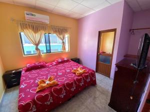 Un dormitorio con una cama roja con corazones. en La Casa de Jeimy en Puerto Baquerizo Moreno