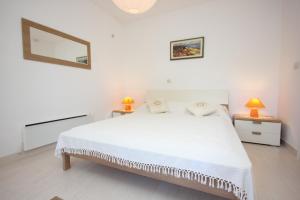 ein weißes Schlafzimmer mit einem weißen Bett und zwei Lampen in der Unterkunft Apartments by the sea Kolocep, Elafiti - 2182 in Koločep