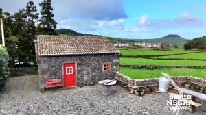 a small house with a red door in a field at Welcome to Paradise in Angra do Heroísmo