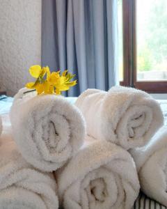 a pile of towels on a bed with a yellow flower at El Torreón Lodge in Potrerillos