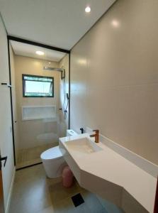 a white bathroom with a toilet and a sink at Casa 3 suítes vista natureza in Ubatuba