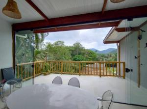a table and chairs on a balcony with a large window at Casa 3 suítes vista natureza in Ubatuba