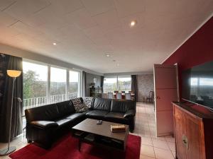sala de estar con sofá de cuero negro y TV en Cosy holiday home in Andenne with terrace, en Andenne