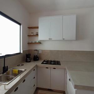 a kitchen with white cabinets and a sink and a window at Ap 01 apartamento Beira mar in Pontal do Paraná