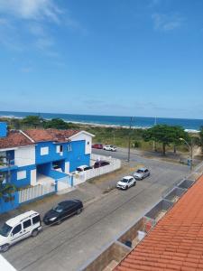 uma rua com carros estacionados em frente a um edifício azul em Ap 01 apartamento Beira mar em Pontal do Paraná