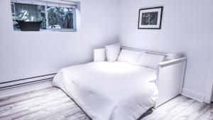 a white bedroom with a bed and a window at Small Private Studio at Kitsilano Beach in Vancouver