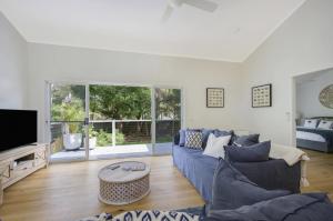 Macmasters BeachにあるFamily Friendly Beach House - 5mins walk to the beachの青いソファとテレビのあるリビングルーム