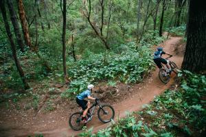 two people riding bikes on a dirt trail in the woods at The Roozen Residence in Prevelly