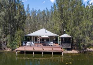 a dock with chairs and umbrellas on the water at Sweetacres Hunter Valley in Pokolbin