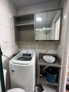 une petite salle de bains avec un lave-linge et un lavabo dans l'établissement Apartamento central próximo da praia e atlântico shopping, à Balneário Camboriú