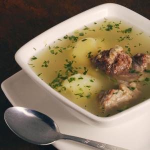 a white bowl of soup with meatballs and a spoon at The Frailejon House in Bogotá