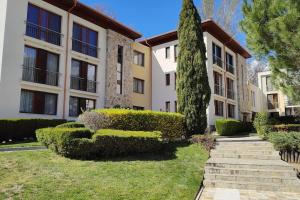 an apartment building with a tree in the yard at Modern 2BDRM in 5* Resort & pool in Sandanski
