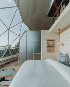 a bedroom with a large white bed and glass walls at Ona Geo Dome At El Mstico in Nogal