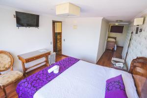 a bedroom with a bed with a purple blanket at Hotel Vista Velero in Viña del Mar