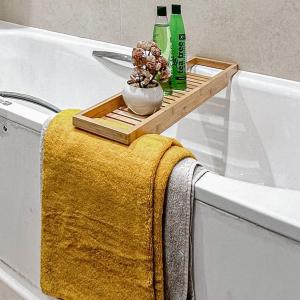 a tray on the side of a bath tub with bottles and a towel at Preciousluxurysuit in Bromley