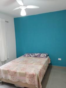 um quarto com uma parede azul e uma cama em Cantinho do descanso em Bertioga