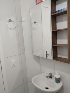 uma casa de banho branca com um lavatório e um espelho em Cantinho do descanso em Bertioga