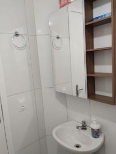 a white bathroom with a sink and a mirror at Cantinho do descanso in Bertioga
