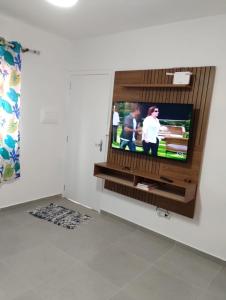 uma televisão de ecrã plano numa parede numa sala de estar em Cantinho do descanso em Bertioga