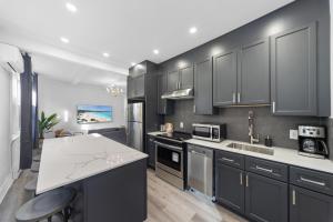 een keuken met zwarte kasten en een wit aanrecht bij Modern and cozy 4 bedrooms sleep 12 in Montreal