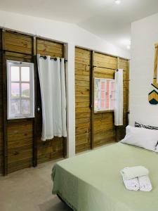 a bedroom with a bed and two windows at Suítes Cabanas Coral in Serra