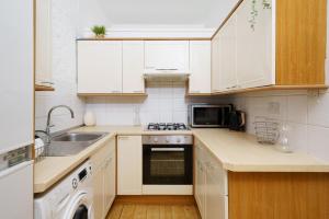a kitchen with white cabinets and a stove top oven at Modern 4-bedroom Apartment in Fulham, London in London