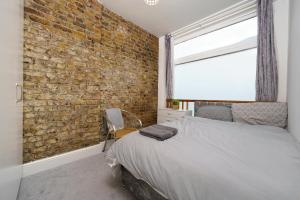 a bedroom with a brick wall and a bed at Modern 4-bedroom Apartment in Fulham, London in London