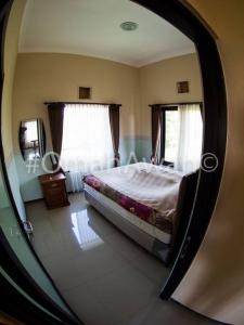 a reflection of a bedroom with a bed in a mirror at Omah Awan at Desa Wisata Petik Jeruk Selorejo in Sengon