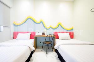 um quarto com 2 camas e uma secretária com uma cadeira em Hotel Capital Cikokol RedPartner em Kebonnanas
