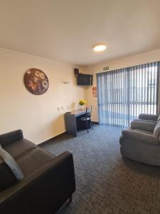 sala de estar con sofá y escritorio en Avenue Heights Motel, en Whangarei