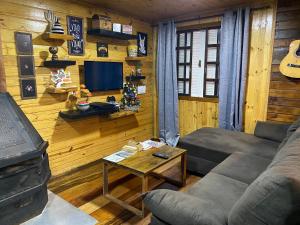 a living room with a couch and a table and a tv at Morada das Estrelas in Cambara do Sul