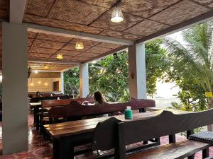 a woman sitting at a restaurant with tables and chairs at Lae Tawan Bungalow in Koh Chang Ranong