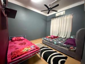 a bedroom with two beds and a ceiling fan at Family's Homestay in Kuala Terengganu