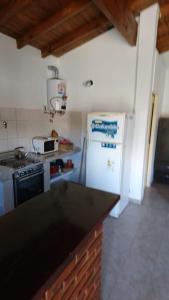 Il comprend une cuisine équipée d'un réfrigérateur blanc et d'une cuisinière. dans l'établissement CASA PARA DESCANSAR, à Mar del Tuyú
