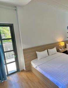 a bedroom with a white bed and a window at Bamboo Hotel Vung Tau in Vung Tau
