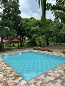 a large blue swimming pool with trees in the background at Apartaestudio Villa Mary-Aguachica in Aguachica