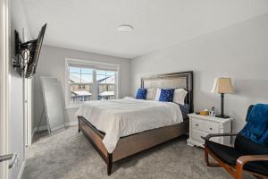 1 dormitorio con cama, ventana y silla en Newly Built Family Townhome, Sleeps 12 Comfortably, en Airdrie